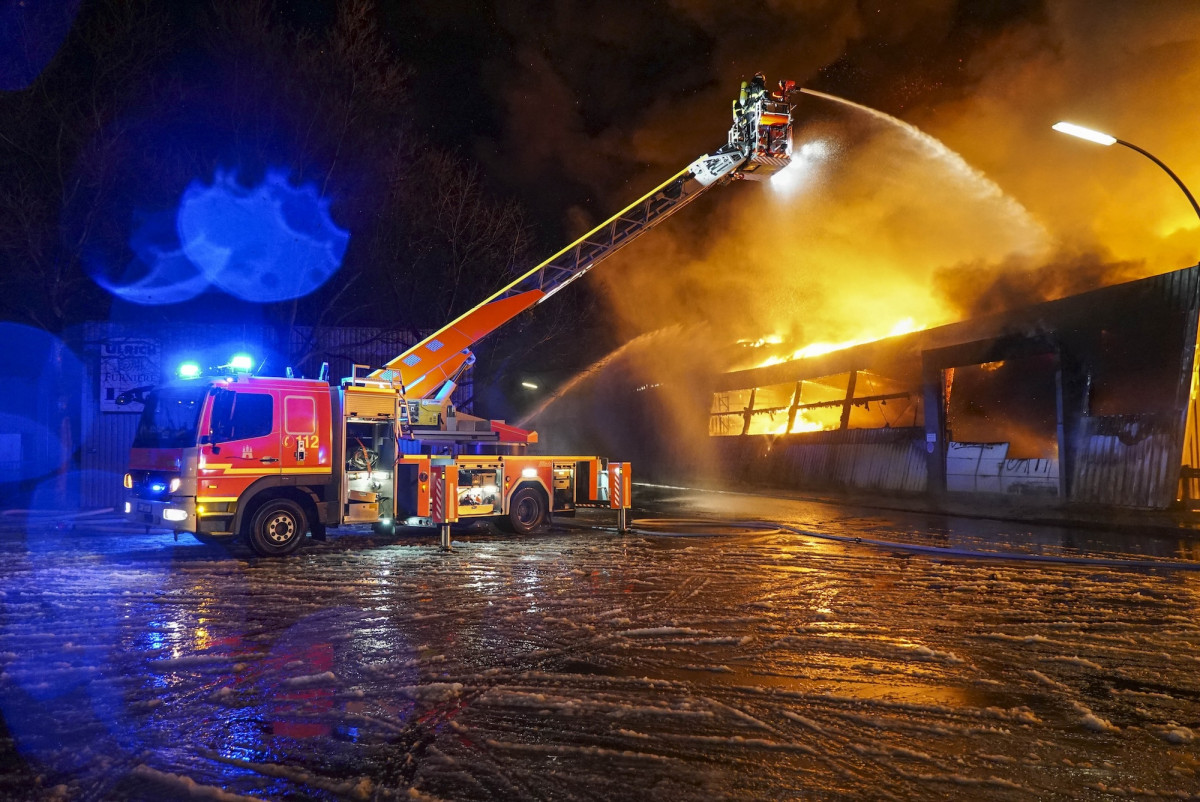 Ein Löschfahrzeug löscht brennende Container in der Nacht