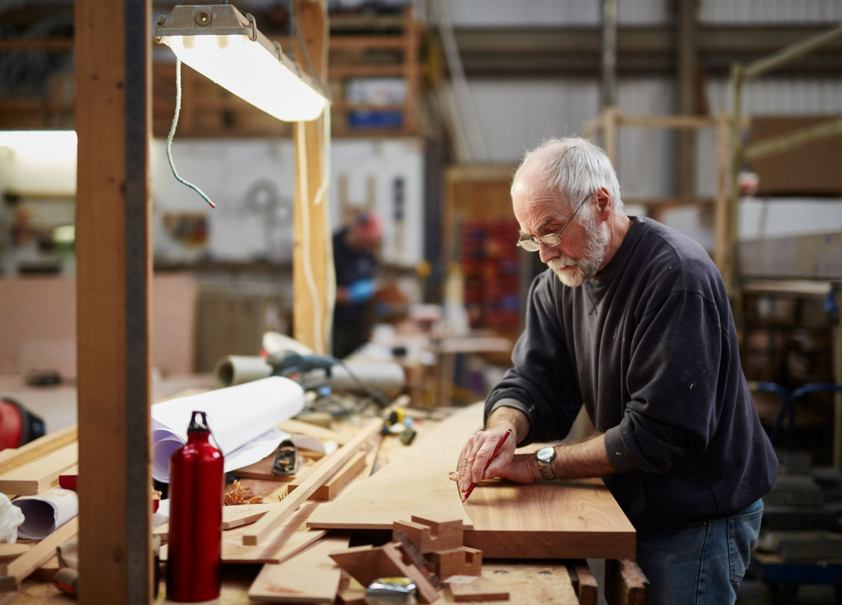 Ein alter Mann arbeitet mit Holz