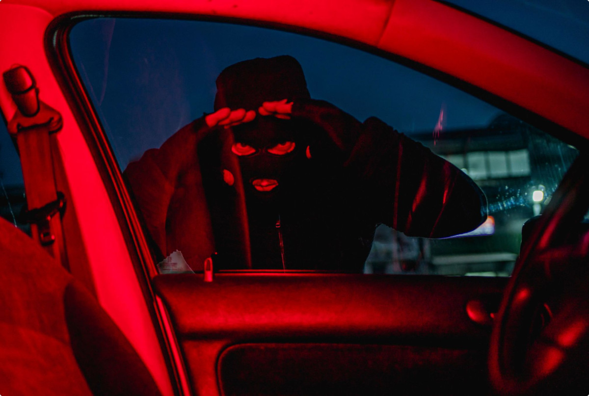 Mann mit Maske späht in ein Auto