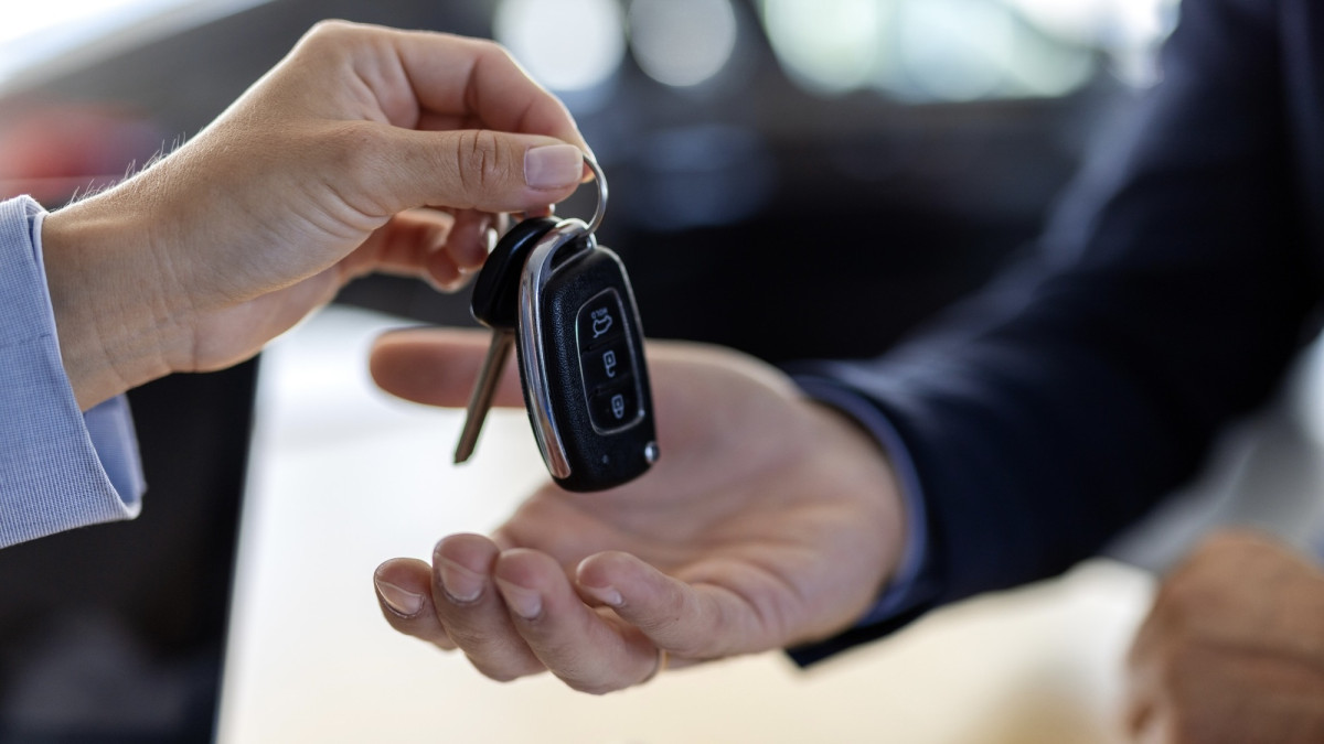 Autoverkäufer übergibt Autoschlüssel