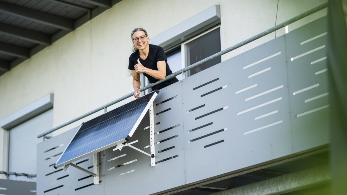 Frau glücklich nach Installation eines Solarpanels auf dem Balkon