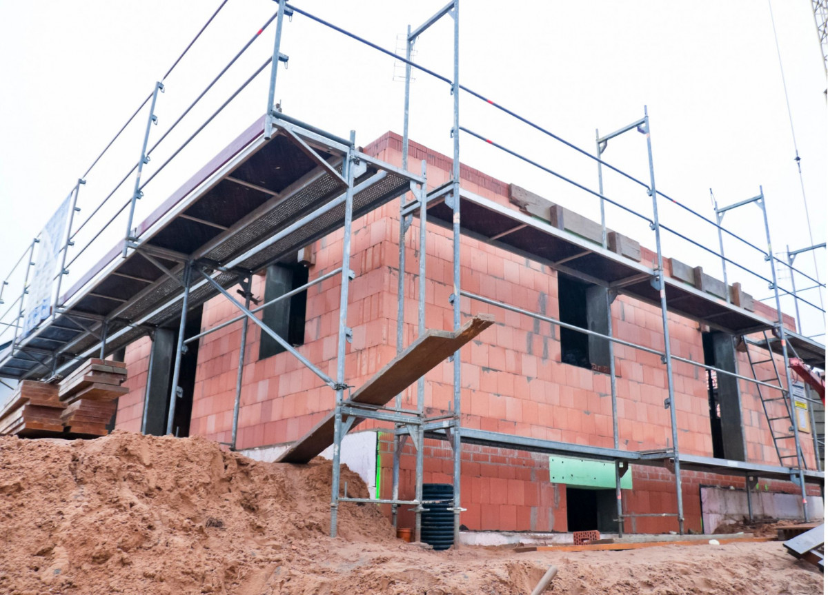 Der Rohbau eines Hauses, um den ein Baugerüst steht.