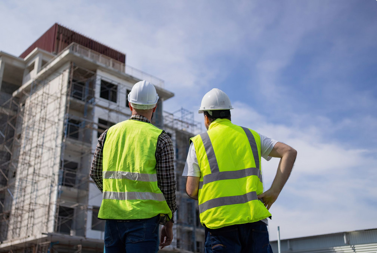 Zwei Bauarbeiter begutachten ein Haus