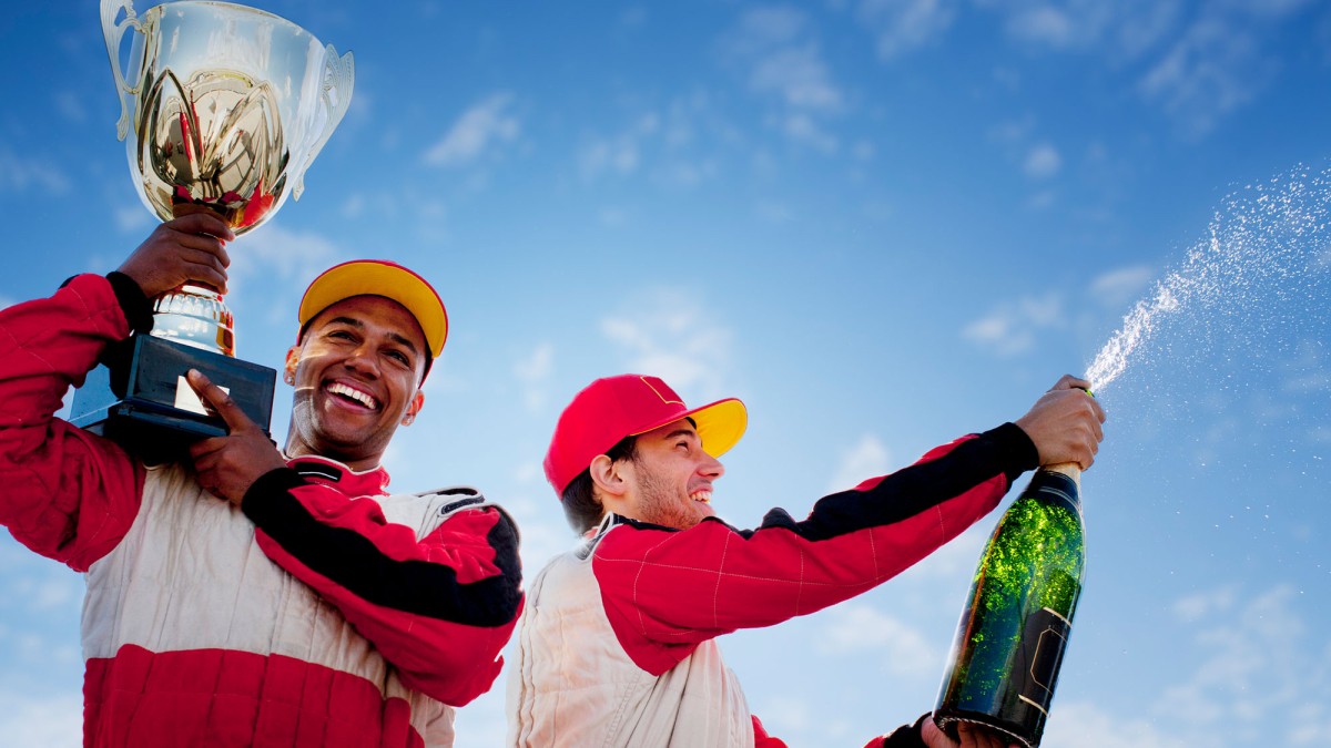 Rennfahrer mit Champagner und Pokal