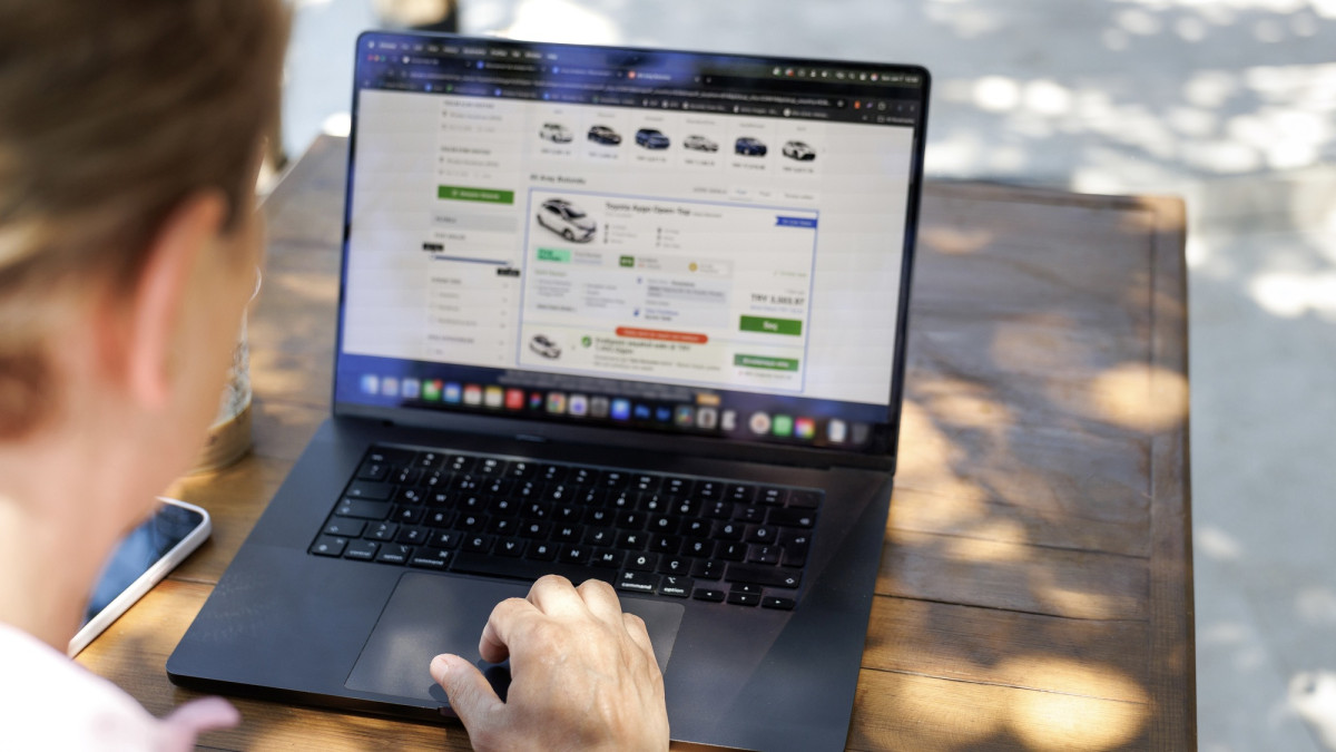 Frau vergleicht Fahrzeugpreise auf Laptop