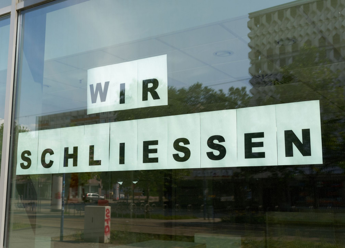 Schild mit Aufschrift "Wir schließen" hängt in einem Schaufenster