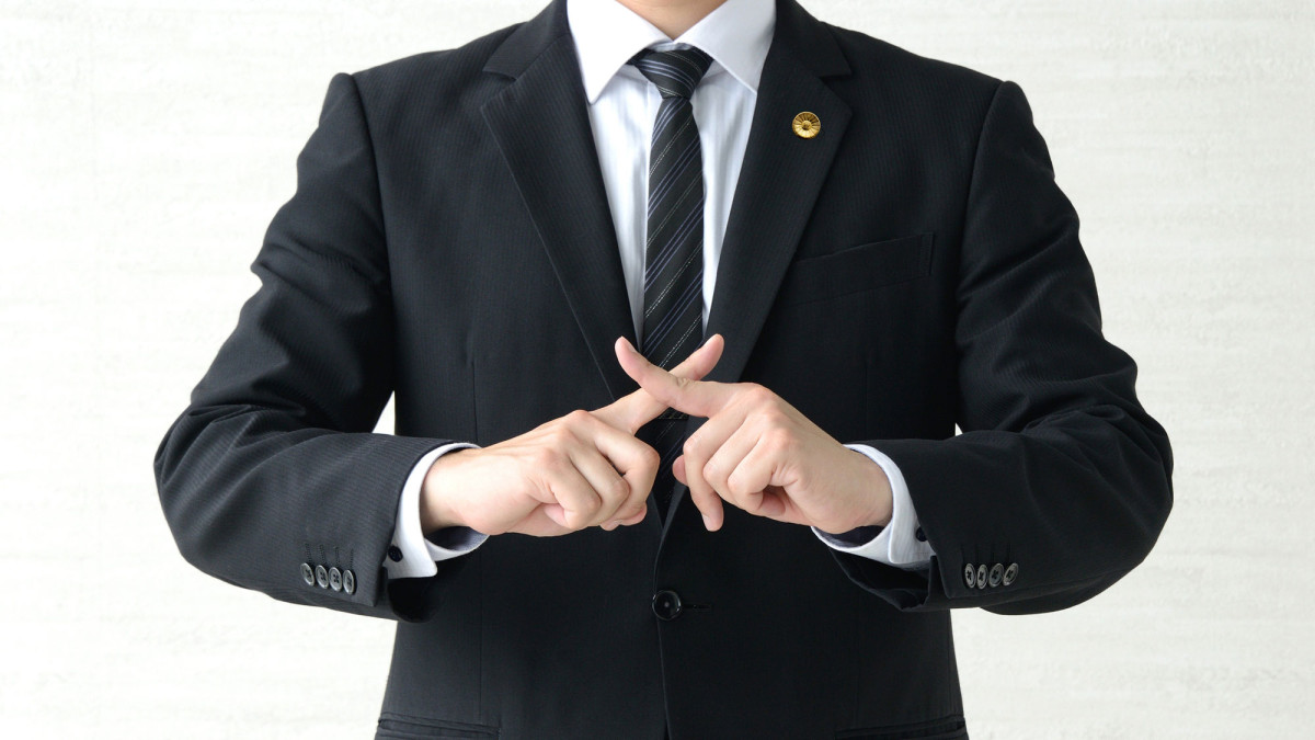 Mann mit überkreuzten Zeigefingern