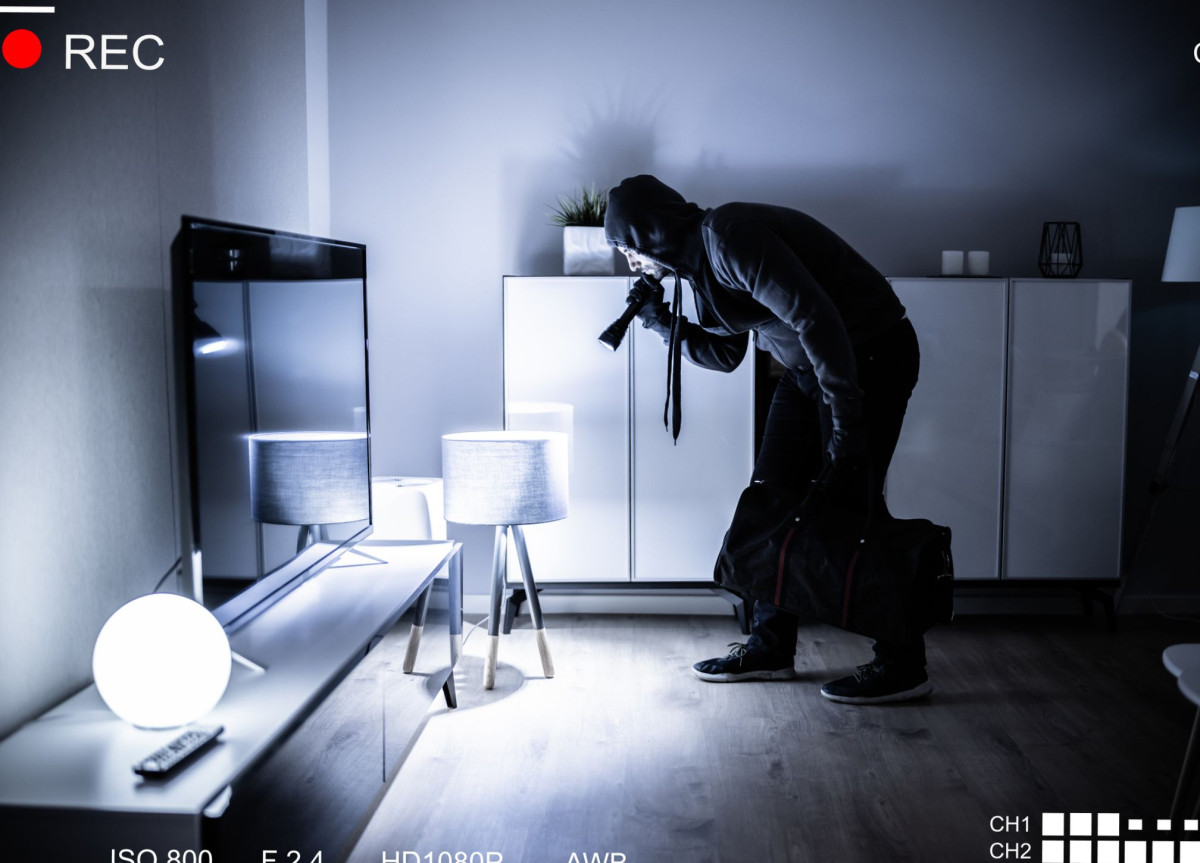 Ein Einbrecher geht mit einer Taschenlampe durch eine dunkle Wohnung