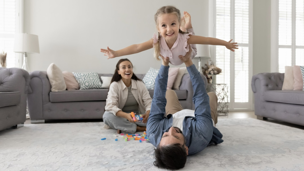 Glücklicher Vater, der seine kleine Tochter in die Luft hält
