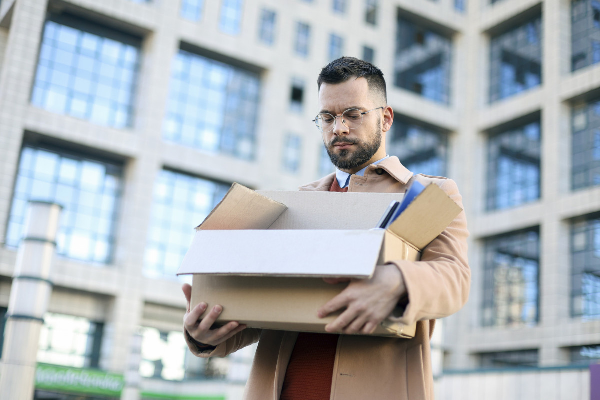 Entlassener Mitarbeiter vor Bürogebäude