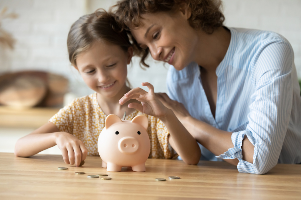 Mutter und Kind werfen Geld in ein Sparschwein
