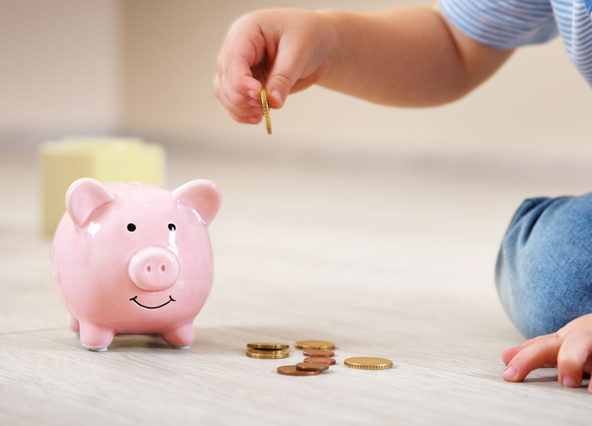Ein Kind wirft Kleingeld in ein Sparschwein