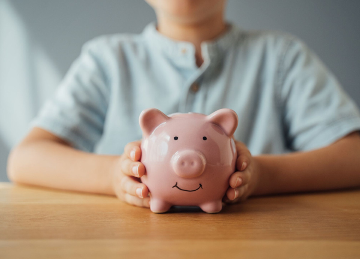 Ein Kind hält ein Sparschwein in seinen Händen