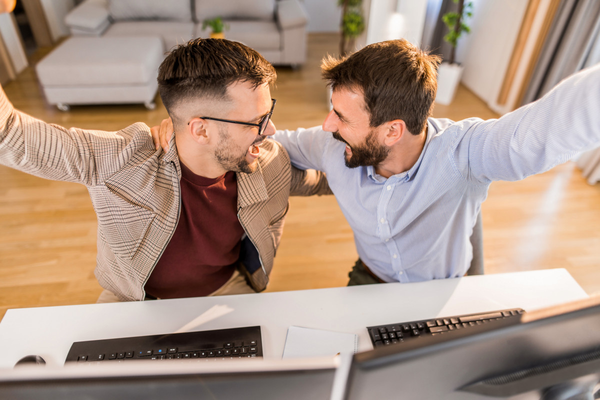 Zwei Männer sitzen im Büro und freuen sich