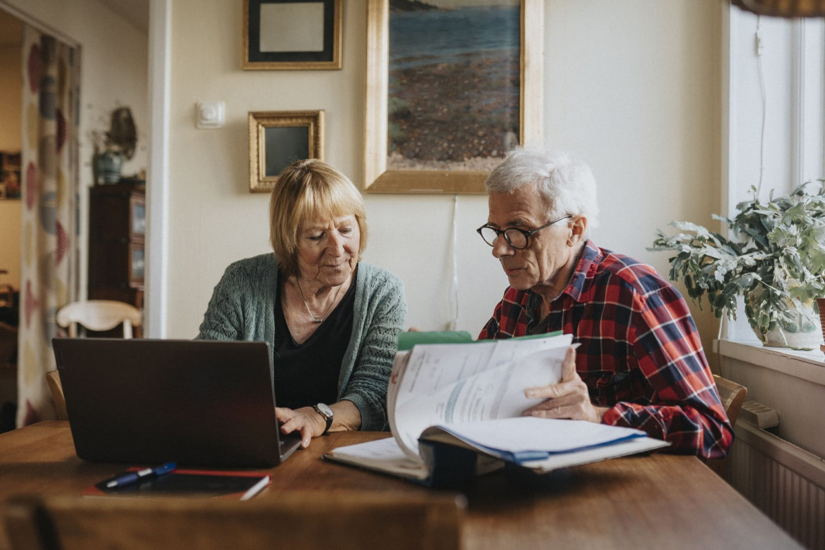 Ein älteres Ehepaar berechnet am Computer ihre Rentenbezüge