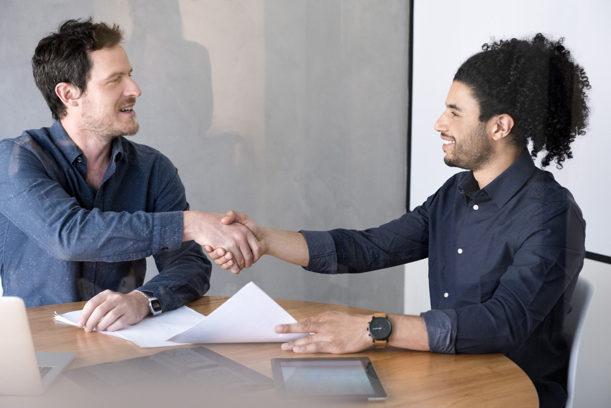 Zwei Männer geben einander die Hände.