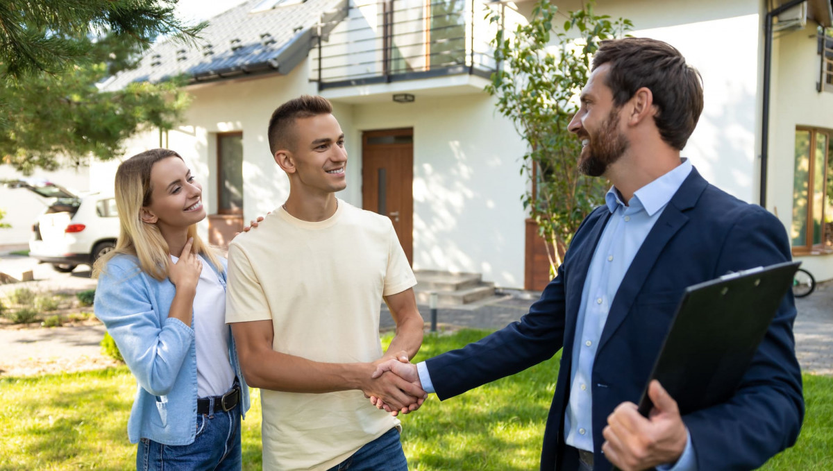 Makler übergibt ein Haus an ein junges Paar