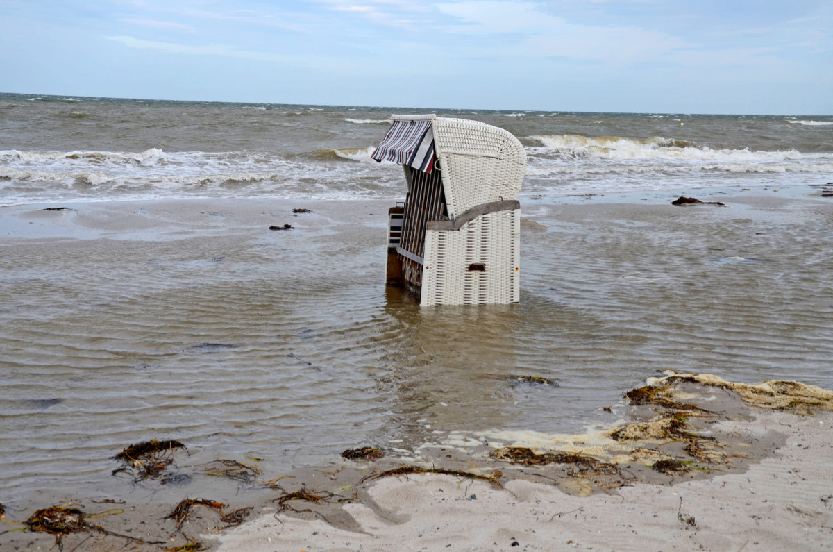 Strandkorb steht auf einem überfluteten Strand.