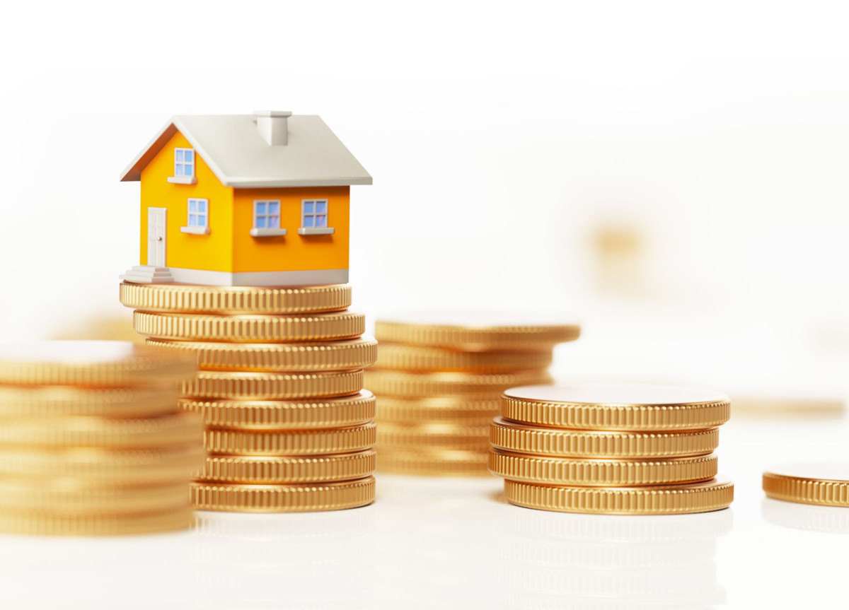 Ein kleines Modellhaus steht auf einem Stapel Geldmünzen