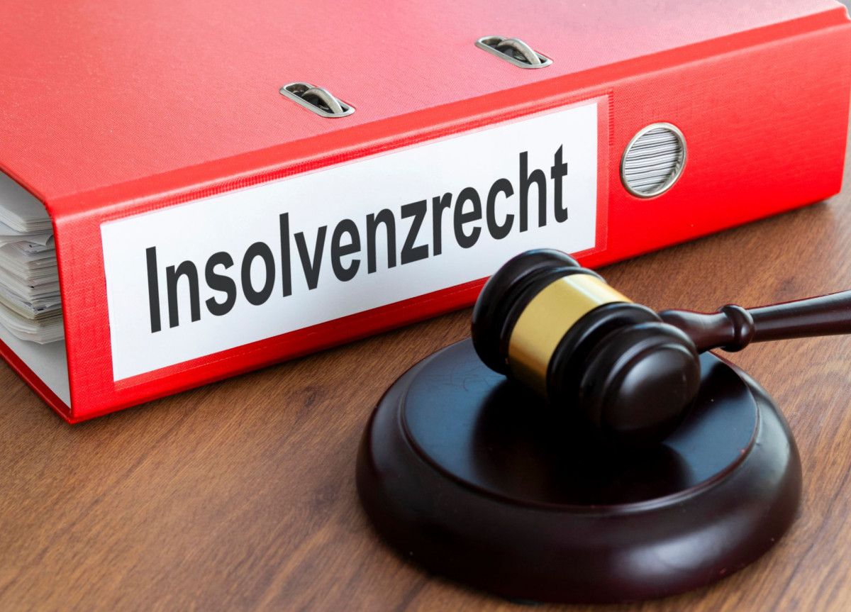 Ein roter Ordner mit der Aufschrift "Insolvenzrecht" liegt neben einem Richterhammer