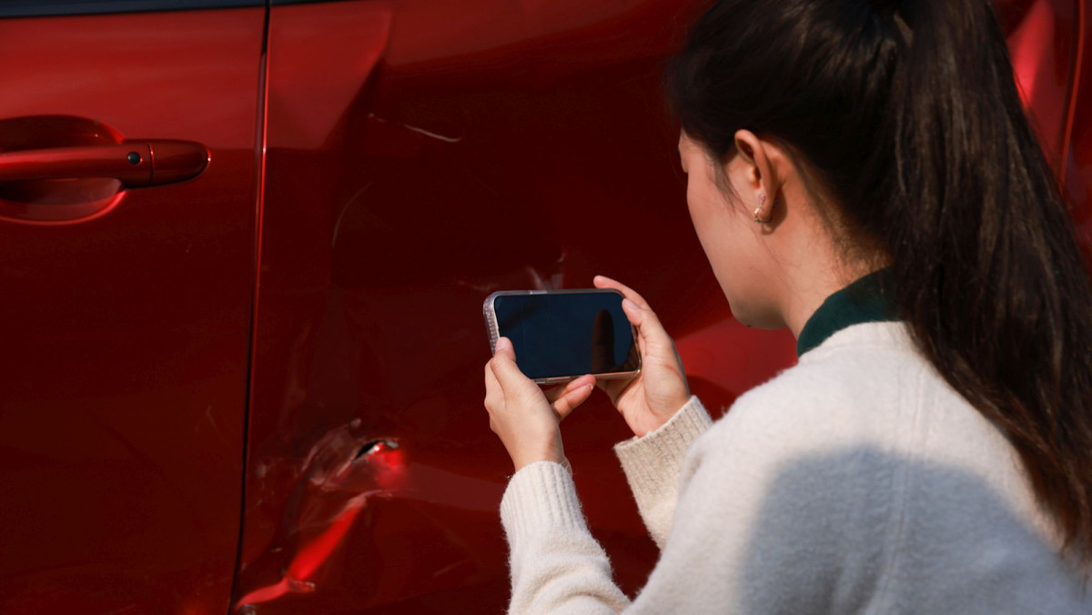 Frau fotografiert Schaden an Auto