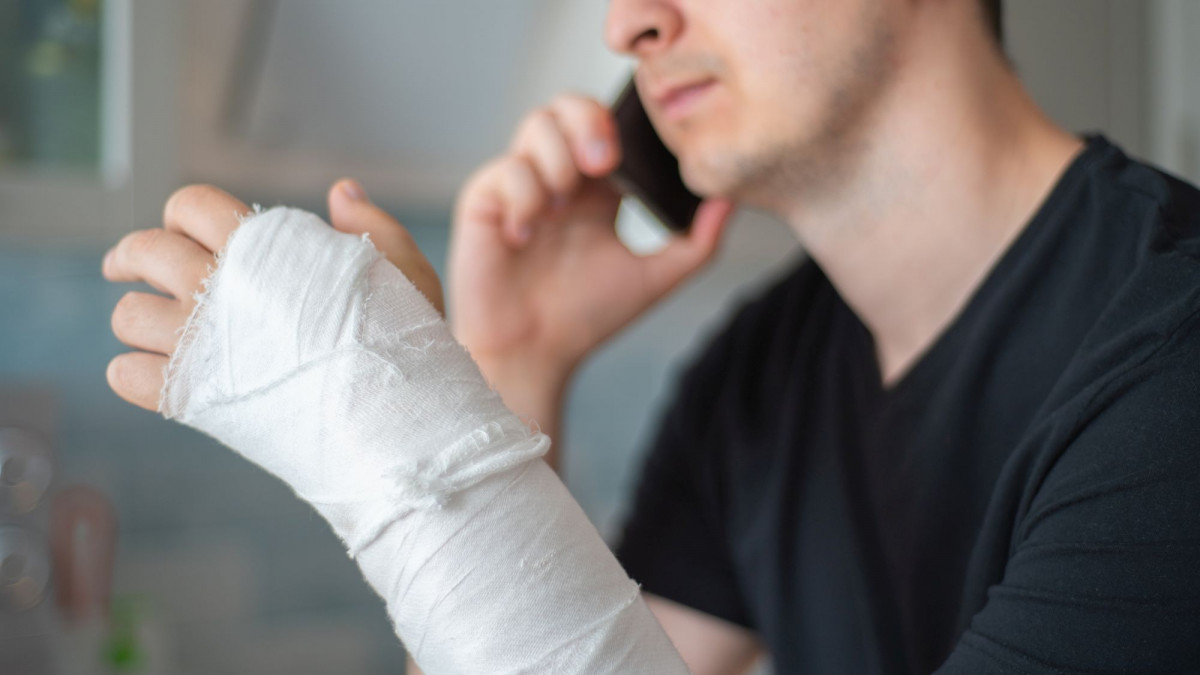Mann mit gebrochenem Arm telefoniert