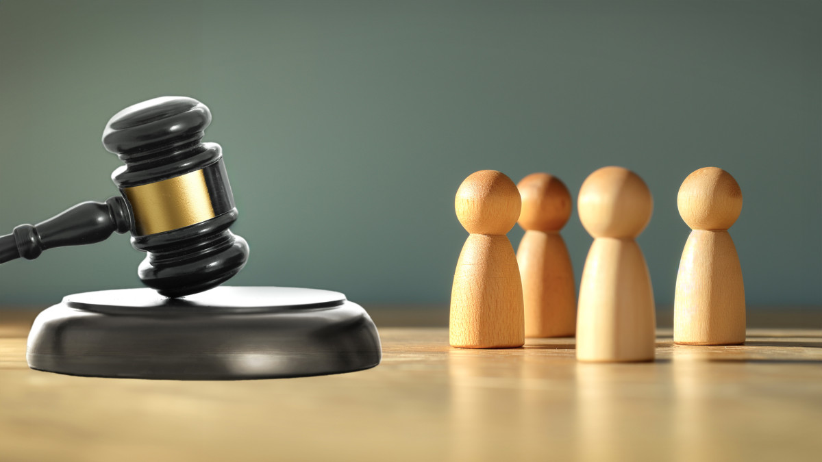 Mehrere Holzfiguren stehen vor einem Richterhammer