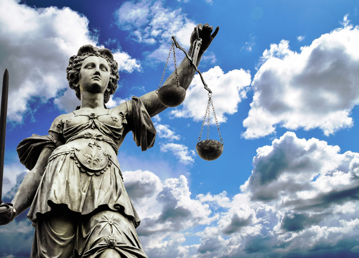 Eine Statue der Justitia vor einem wolkigen Himmel