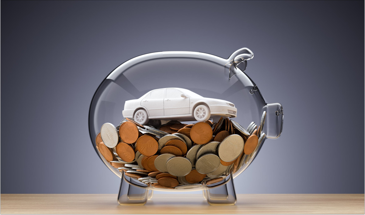 Ein gläsernes Sparschwein enthält Münzen und ein kleines Auto