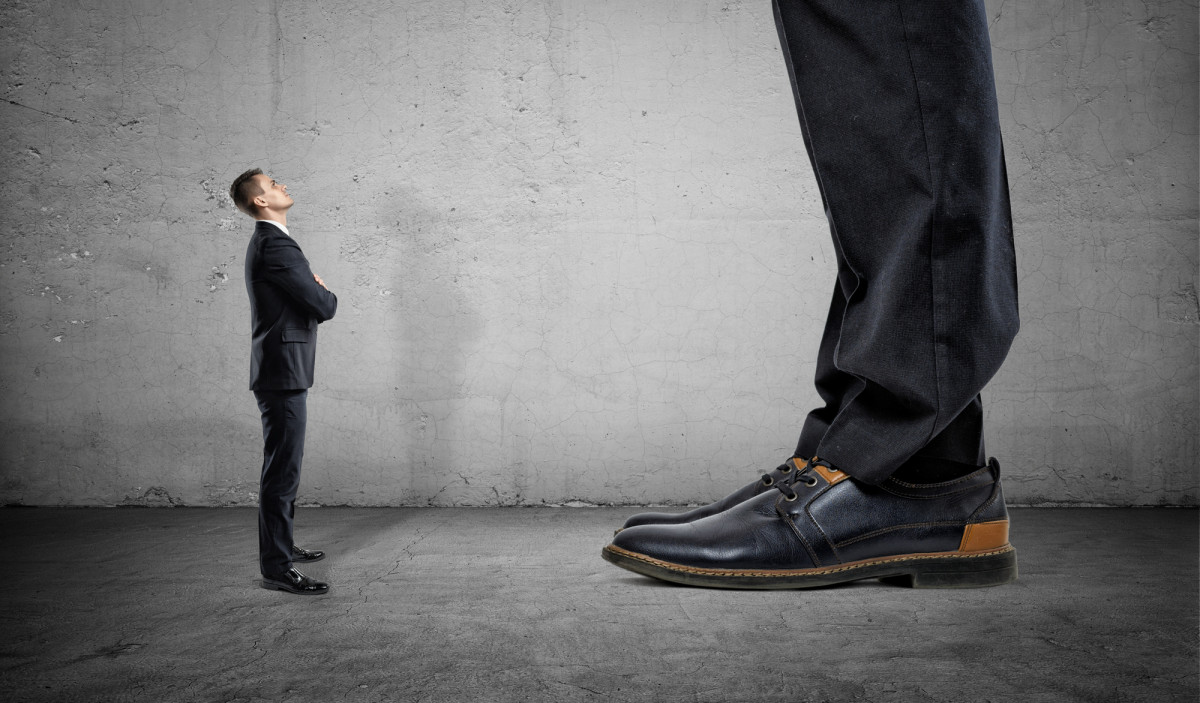 Winziger Geschäftsmann, der auf riesigen Beinen eines anderen Mannes nach oben schaut