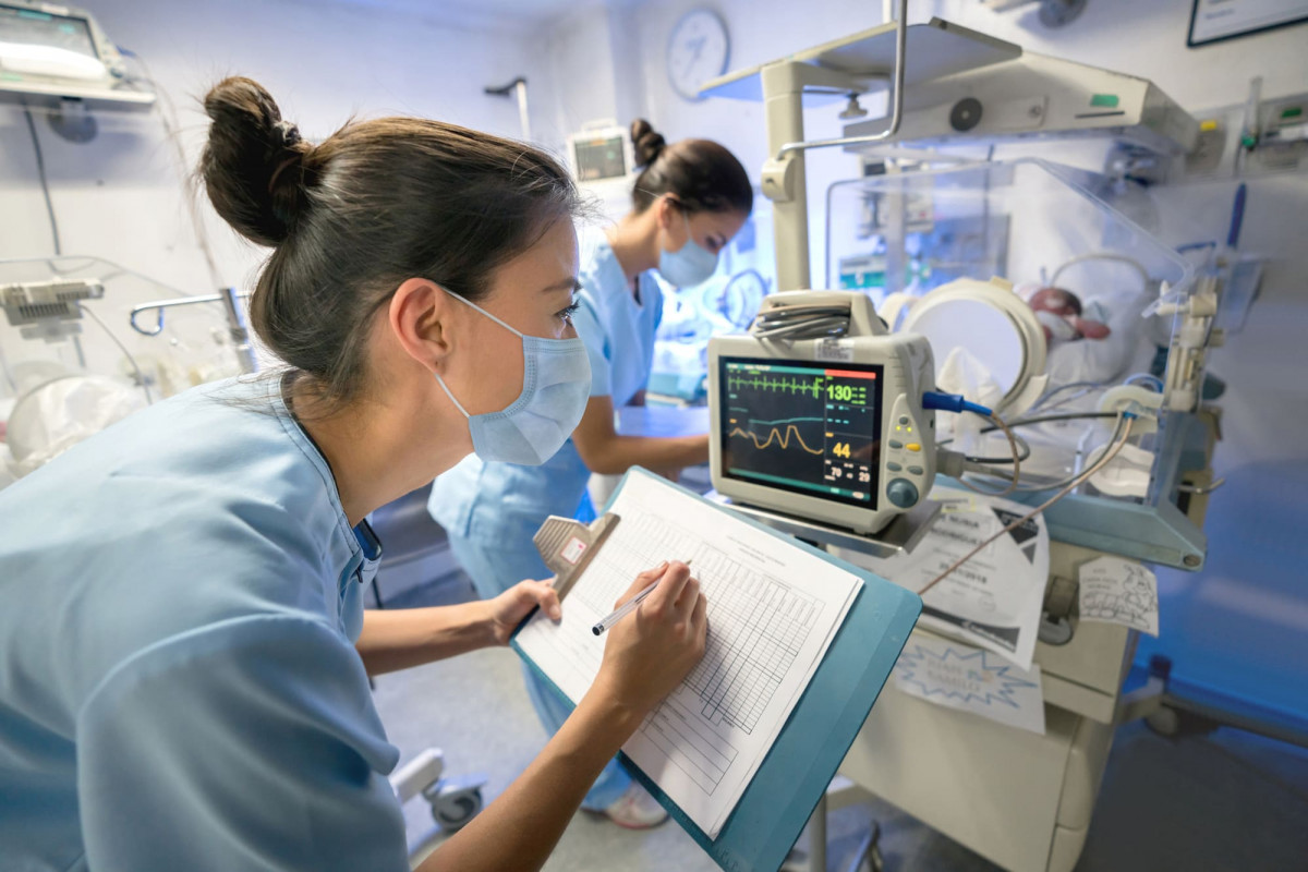 Krankenschwester überwacht ein frühgeborenes Neugeborenes in einem Brutkasten