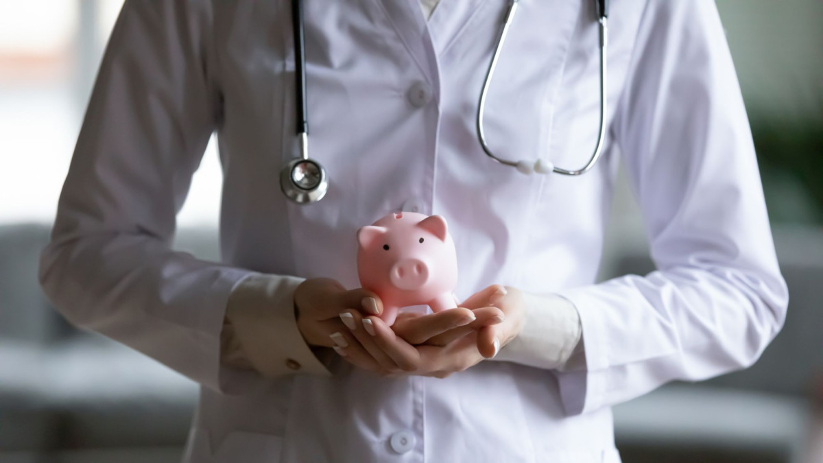 Arzt hält Sparschwein in der Hand