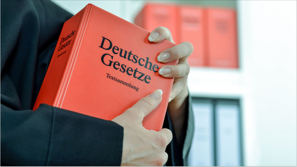 Eine Richterin hält ein Buch mit der Aufschrift "Deutsche Gesetze"