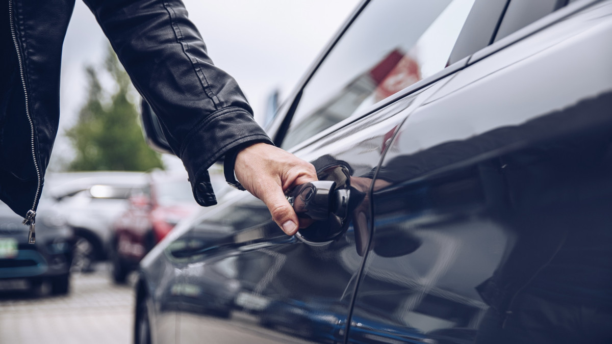 Mann greift nach dem Autotürgriff