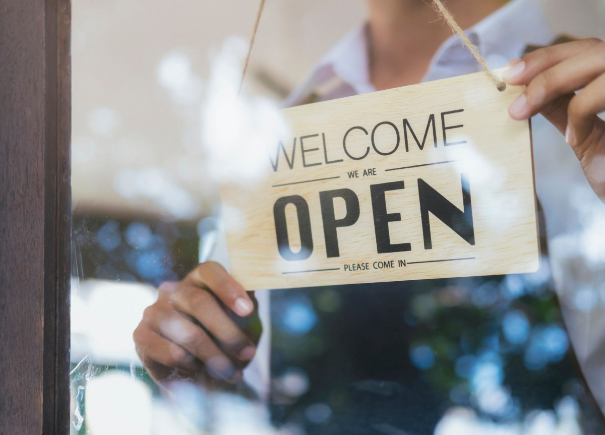 Ein Mann hängt ein "Open"-Schild in die Tür