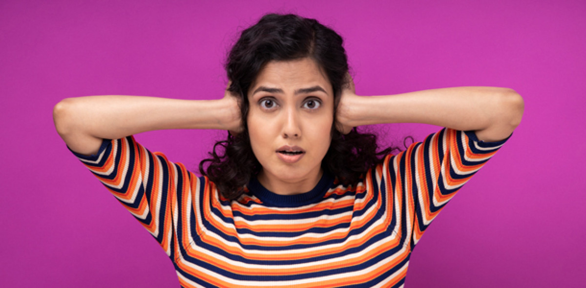 Junge Frau hält sich die Ohren zu