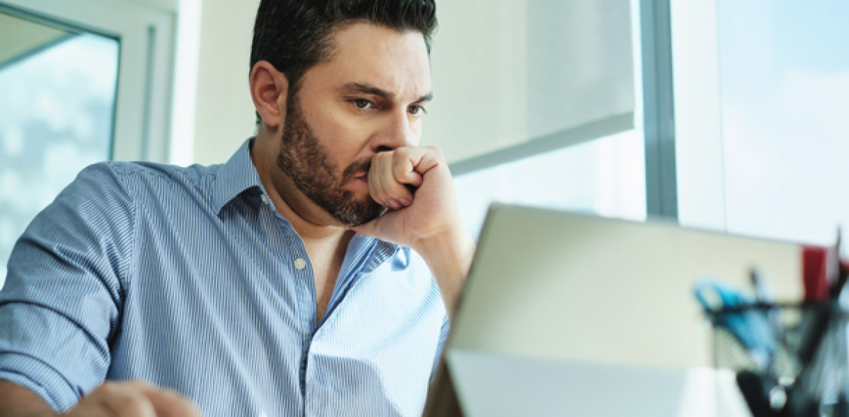 Mann schaut misstrauisch auf Laptop