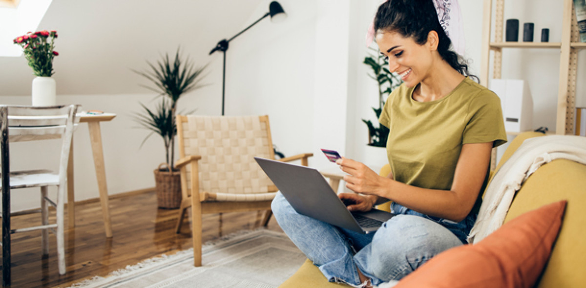 Frau sitzt am Laptop und gibt ihre Zahlungsdaten ein