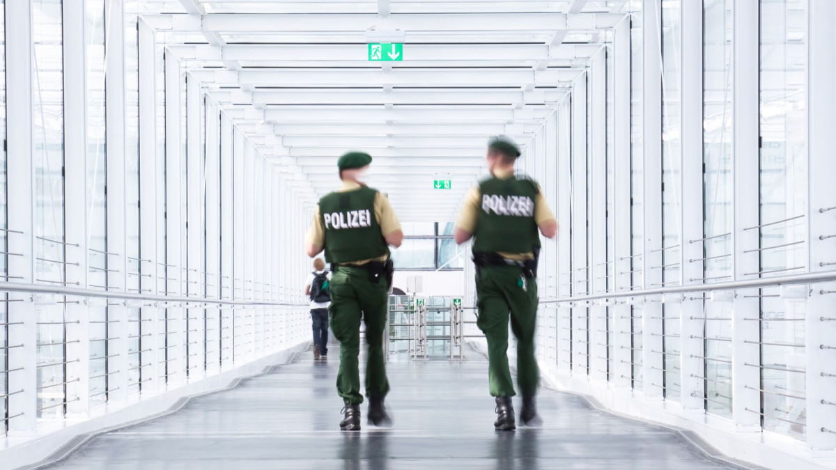 Zwei Polizisten patrouillieren auf einem Flughafengelände.