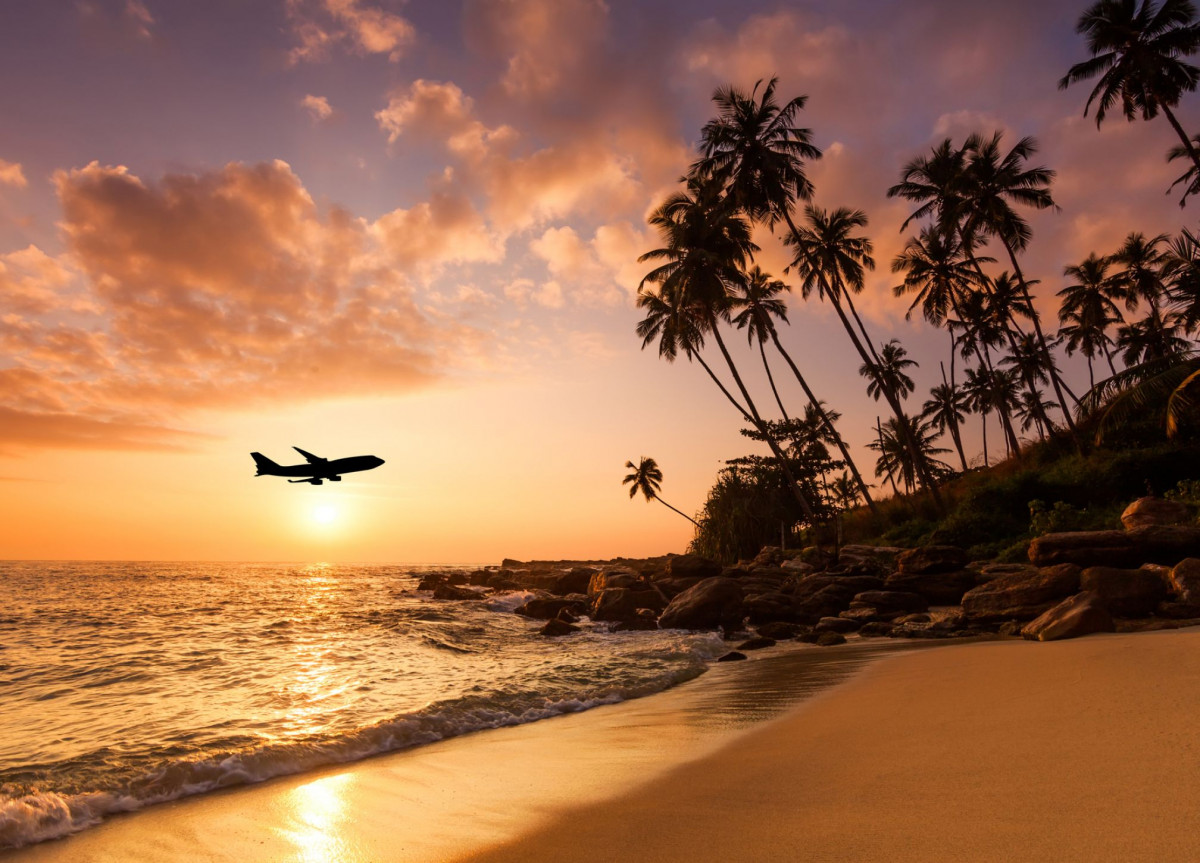 Ein Flugzeug nähert sich im Tiefflug und bei Sonnenuntergang einer Insel