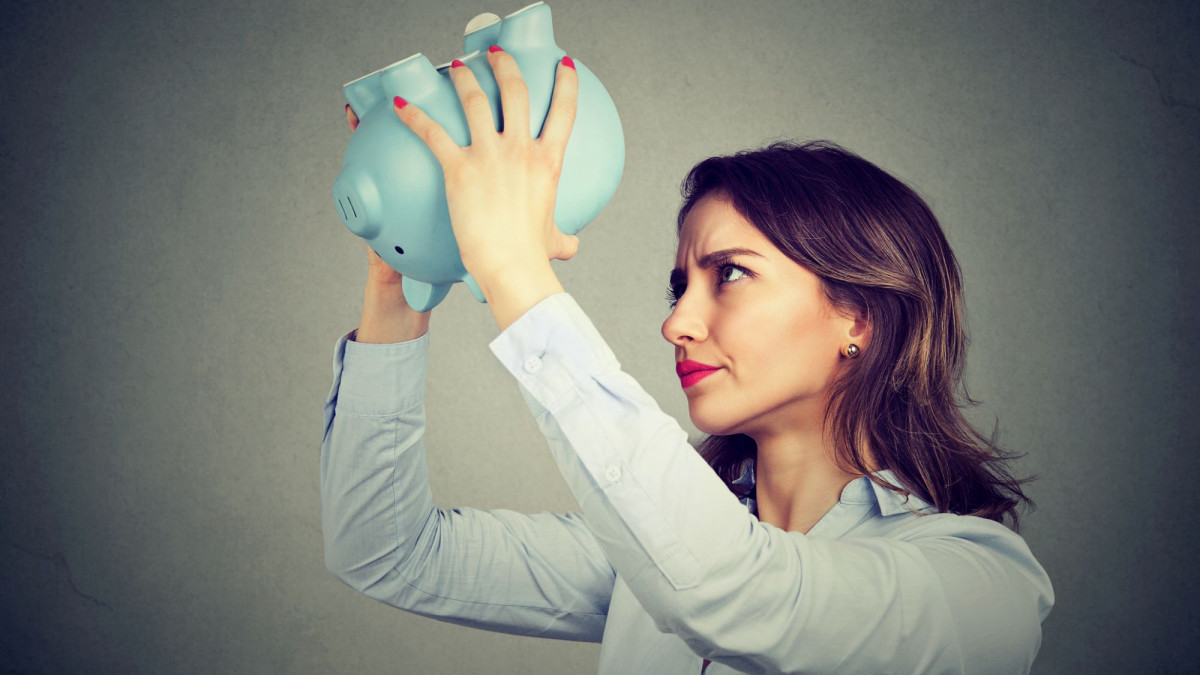 Frau kippt leeres Sparschwein aus