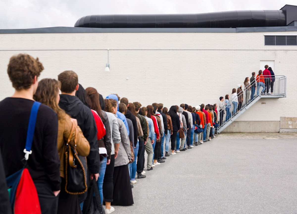 Viele Leute stehen vor einem Gebäude in einer Schlange