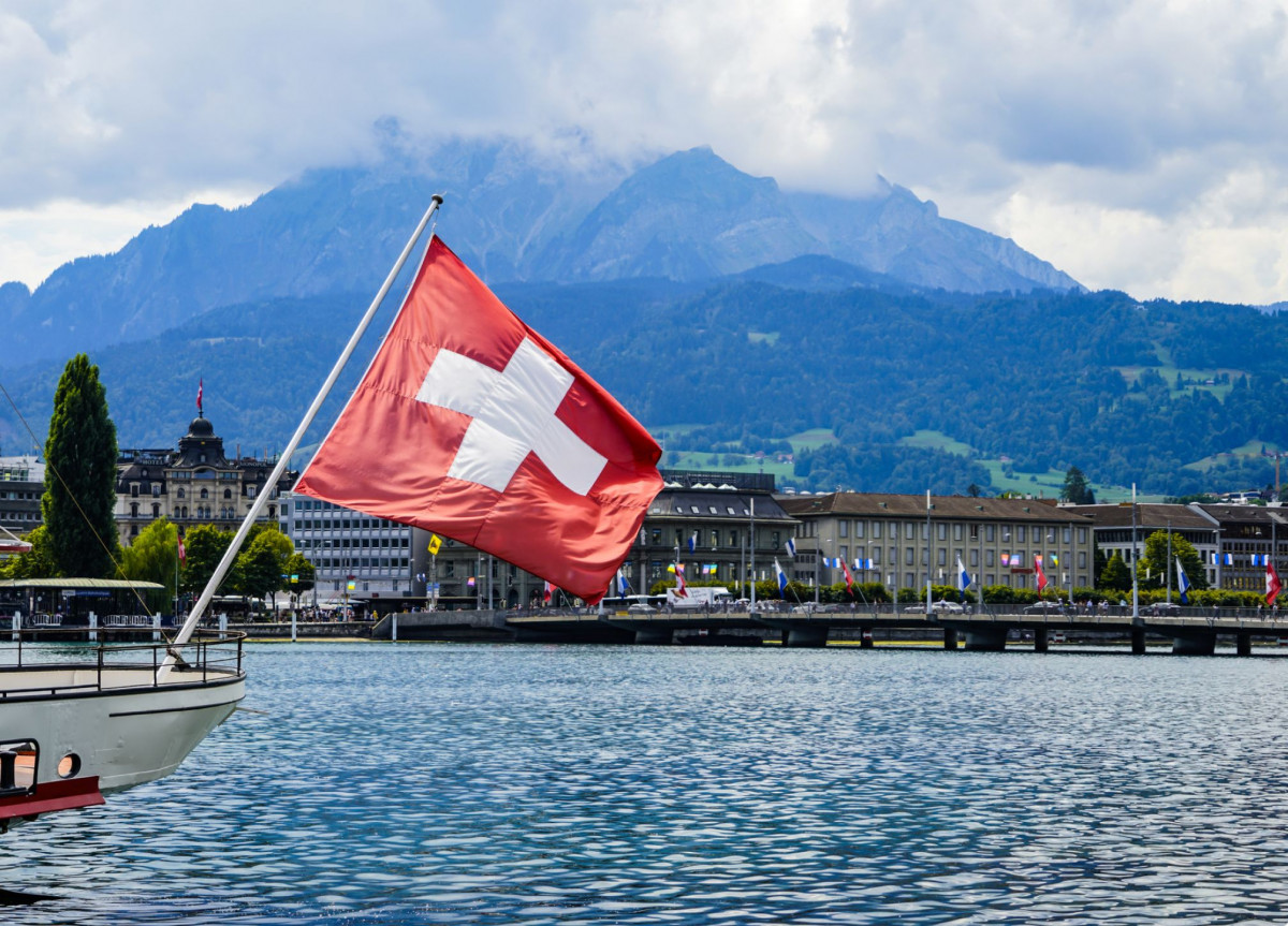 Schweizer Flagge weht über einem See und vor einem Bergpanorama