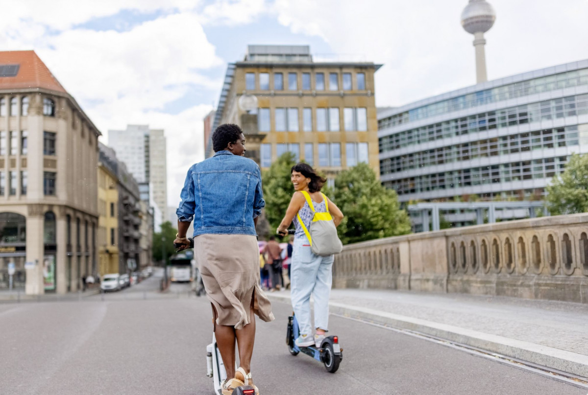 Zwei Menschen fahren auf E-Scootern durch Berlin