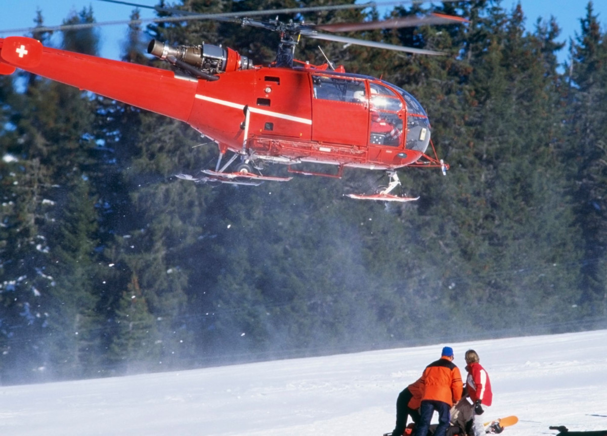 Ein Hubschrauber schwebt über einem verunglückten Skifahrer