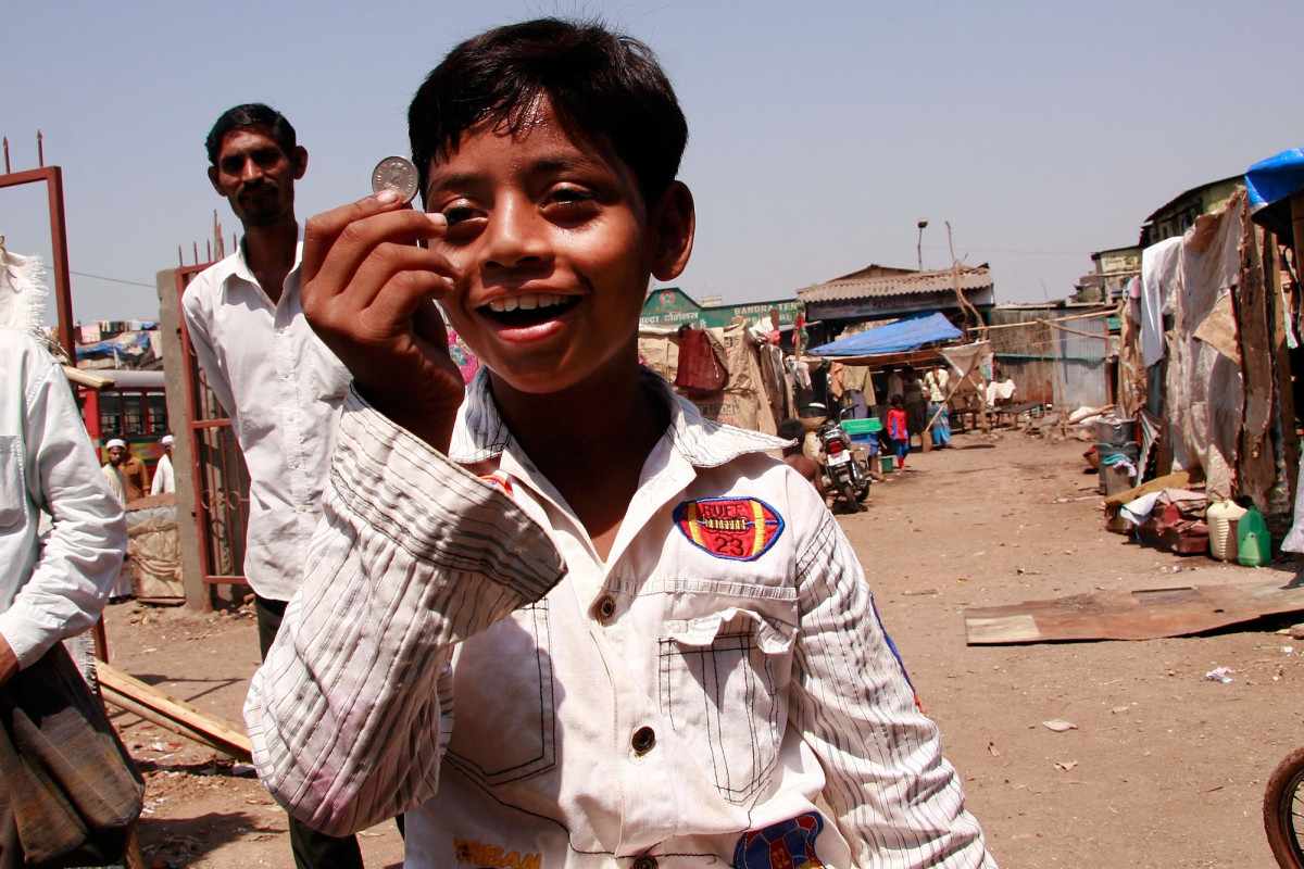 Der Star aus dem Film Slumdog Millionär hält eine Rupie hoch