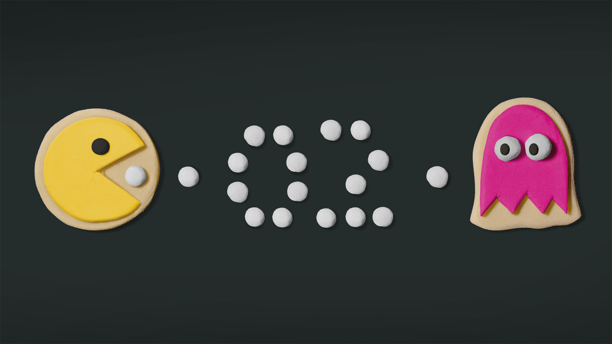 Ein Keks der aussieht wie ein gelbes Pacman frisst weiße Streusel hin zu einem Keks, der aussieht wie ein rosa Monster