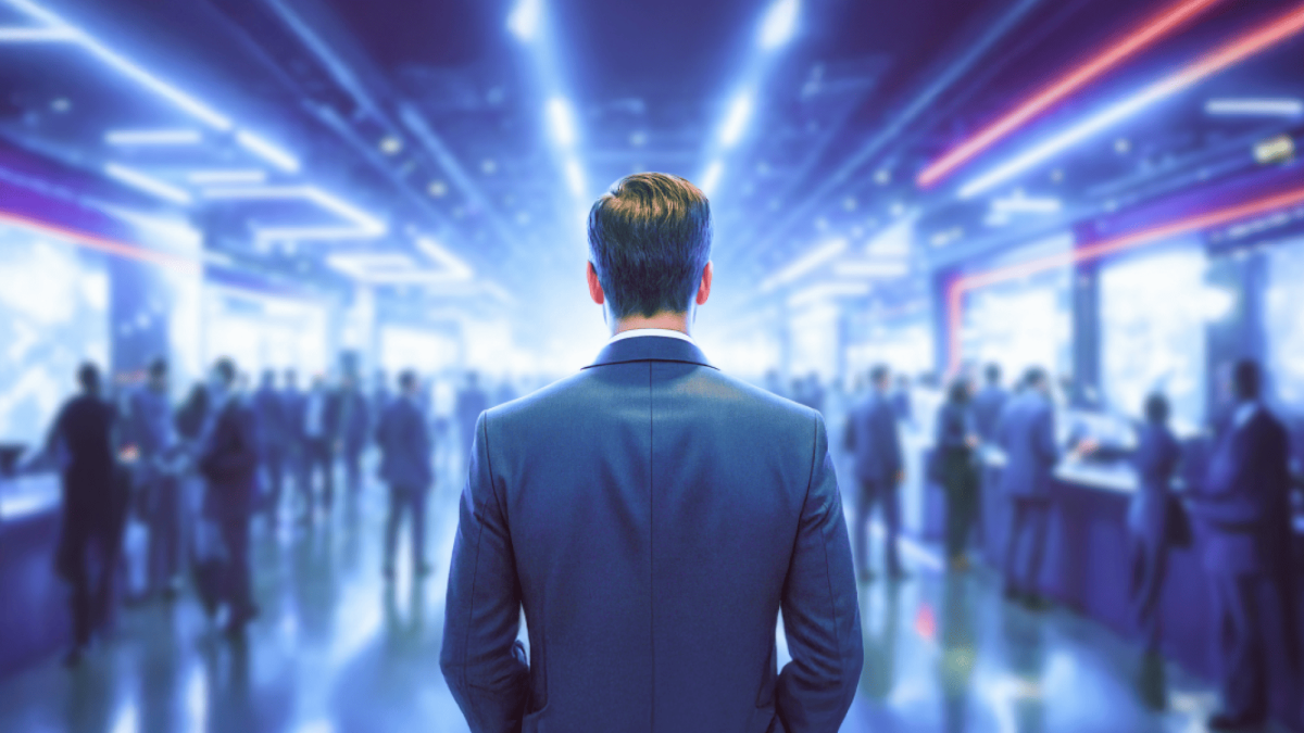 Ein Mann steht in einem hell beleuchteten Raum, in dem sich viele Menschen tummeln