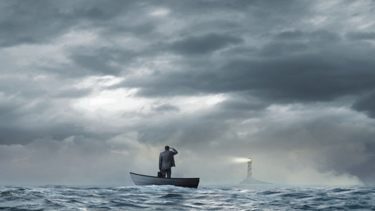 Mann auf Boot schaut Richtung Leuchtturm
