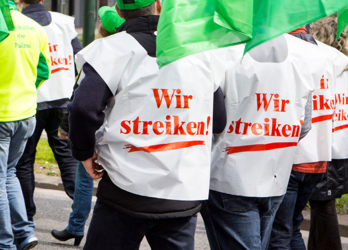 Mehrere Menschen mit "Wir streiken"-Jacken bei einer Protestkundgebung